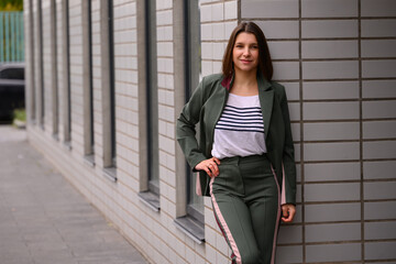portrait of a slender girl in a green suit in natural light against a white wall. natural beauty, no makeup. problematic skin. space for text. High-quality photography