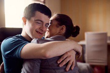 Happy man with down syndrome and his psychologist embrace while greeting at home.