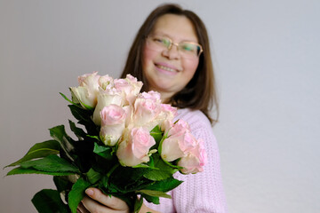 close-up of bouquet of white, pink roses, in hands of adult woman, brought flowers on date with girlfriend, boyfriend, gives to mom, concept of mother's, Valentine's day, birthday, focus in foreground