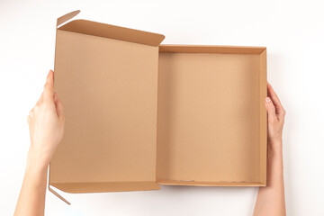 Top view to female hands opening empty brown cardboard box on white background. Mockup parcel box....