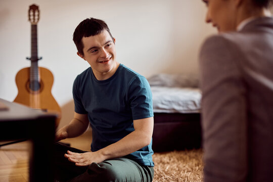 Happy man with down syndrome talks to his therapist during home visit.