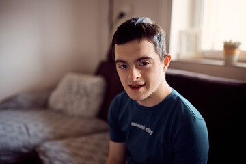 Young happy man with down's syndrome at home looking at camera.