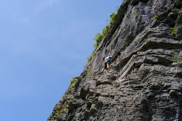man in body harnesses feature life-safety, attaches hooks to iron brackets, climbs rock, active lifestyle of people, mountaineering, via ferrata in mountains of alps, life insurance in extreme sports