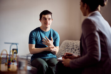 Young down syndrome man talks to his therapist during home visit.
