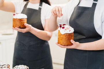 a women decorate icing, dried berries and flowers easter cakes.
