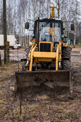 yellow tractor among trees in open air on farm without  driver. Front view. Agricultural machinery. Development of agriculture. Vertical photo