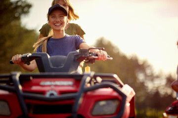 Two female friends are posing for a photo while riding the quad in the nature. Riding, friendship, nature, activity © luckybusiness