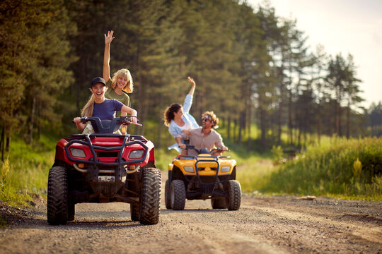Young friends ride quads on a road in the nature.