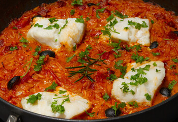 Baked cod with orzo and spicy sausage garnished with chopped parsley