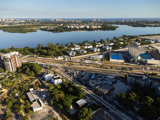 Fototapeta premium Aerial view of Jacarépagua lagoon in Rio de Janeiro, Brazil. Residential buildings and mountains around the lake. Barra da Tijuca beach in the background. Sunny day. Sunset. Drone photo