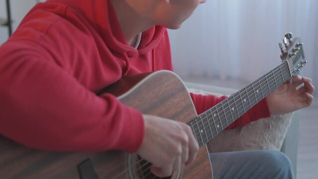 Guitar player. Music education. Creative hobby. Talented focused man guitarist tuning pegs on string instrument practicing musical lesson at home.
