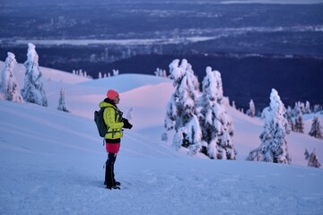 Woman snowshoeing hiking in mountains at sunset looking at scenic views. Winter activity near Vancovuer. Mt Seymour Ski Resort. British Columbia. Canada