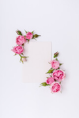Floral creative background with pink roses and empty blank paper