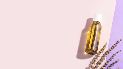 Bottle of lavender essential oil, lavender flowers lying on a light purple background.Cosmetic essential oil for body baths. Phytotherapy, aromatherapy, nutrition of dry skin, selfcare. Copy space
