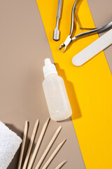 A set of manicure tools, sticks on a background of orange and coffee colors. A bottle of cuticle...
