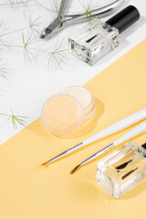 A jar of cuticle nourishing balm, lying on an biege background. A set of manicure tools and...