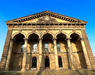 Fototapeta na wymiar Magnificent Victorian stone building, with columns and arches, set against a blue sky on, Bradford Road, Cleckheaton, UK