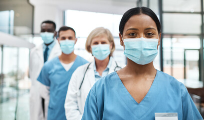 As medical professionals, we have such an important job to do. Portrait of a group of medical practitioners wearing face masks while standing together in a hospital. - Powered by Adobe
