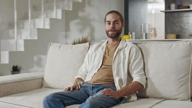 Portrait of male hipster with beard resting on couch
