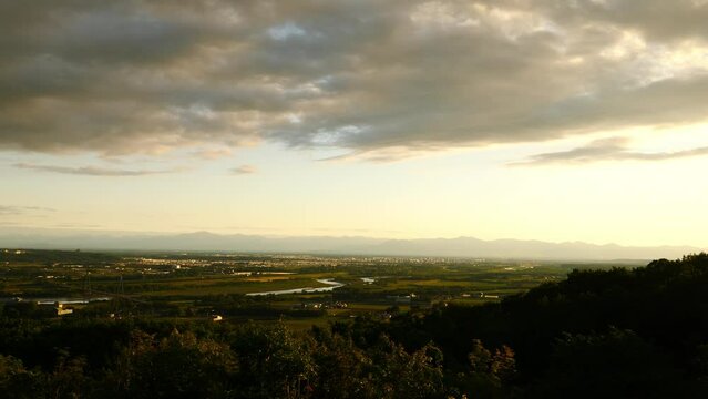 The cityscape of Obihiro and the evening view of the mountains seen from the Tokachigaoka Observatory in Hokkaido. (pan)
