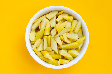 Preserved bamboo shoot in white bowl on yellow background.