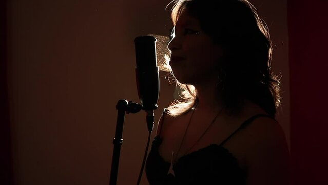 Mujer joven disfrutando del canto. Mujer cantando en estudio.