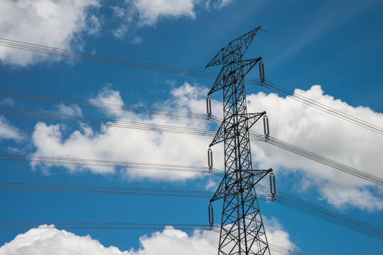 High Voltage Pole Power Transmission Tower With Clear Sky Sunny Day Background. Green Energy, Environmental Conservation Concept.