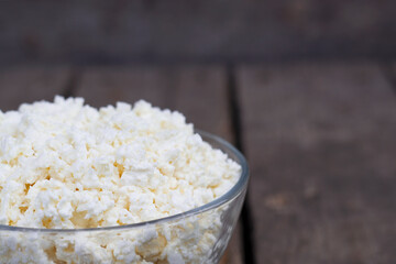 fresh farm cottage cheese in a bowl on wooden background