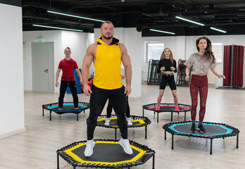 Women's and men's group on a sports trampoline, fitness training, healthy life - a concept trampoline group batut workout healthy, from female athletic in gym from teamwork person, smiling sportswear