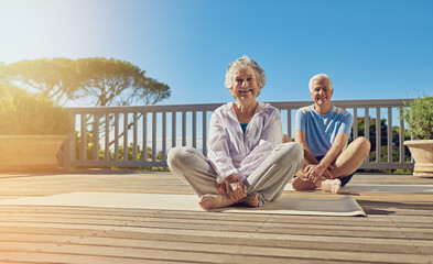 Keeping a healthy mind and body. Shot of a senior couple doing yoga together on their patio outside.