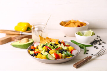 Bowl of tasty Mexican salad with black beans and radish on light wooden table