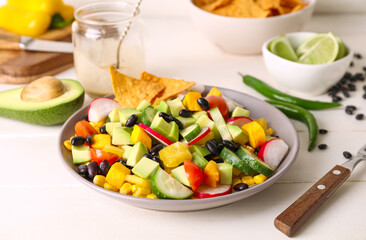 Bowl of tasty Mexican salad with black beans and radish on light wooden table