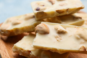 Pieces of tasty chocolate with hazelnuts on board, closeup