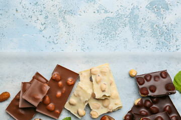Pieces of tasty chocolate with nuts on color background