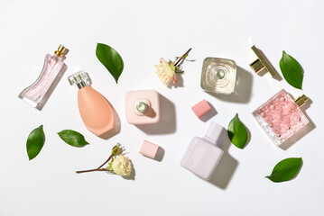Bottles of floral perfumes on light background, top view