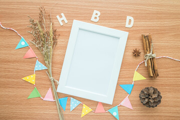 Flat lay of blank photo frame with HBD happy birthday wooden alphabet mockup on wooden table...