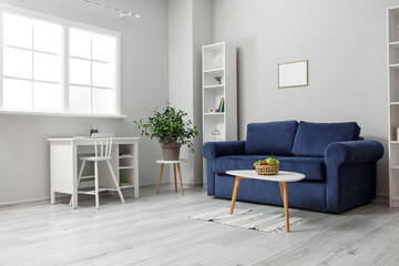 Naklejka na ściany i meble Interior of light living room with blue sofa, table and fruit basket