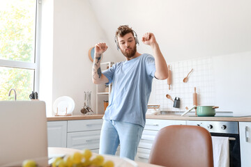 Cool young man with laptop learning to dance at home