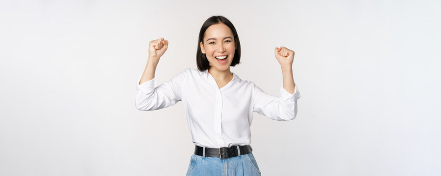 Enthusiastic Asian Woman Rejoicing, Say Yes, Looking Happy And Celebrating Victory, Champion Dance, Fist Pump Gesture, Standing Over White Background