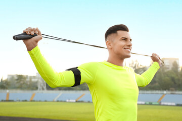 Sporty young man with skipping rope training outdoors