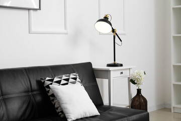 Glowing black lamp on table and sofa near light wall