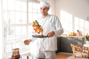 Male chef frying tasty vegetables in kitchen