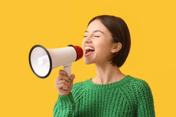 Young woman with megaphone on color background