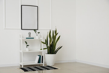 Shelving unit with books and houseplant near white wall