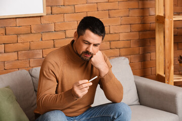 Thoughtful man with cigarette at home. Concept of refusing from bad habit