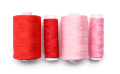 Red and pink sewing thread spools on white background
