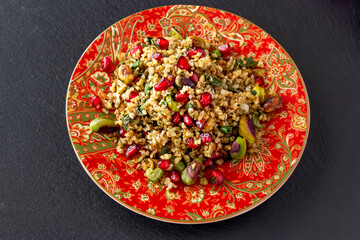 Freekeh, pomegranate seeds and pistachio healthy salad. Arabic, African and Arabic traditional cuisine. Copy space. Superfood concept. Top view.