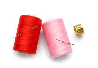 Thread spools with needle on white background