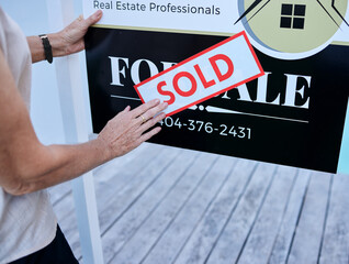 Another property sold. High angle shot of an unrecognizable female real estate agent sticking a...