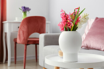 Vase with beautiful hyacinth flowers and candle on table